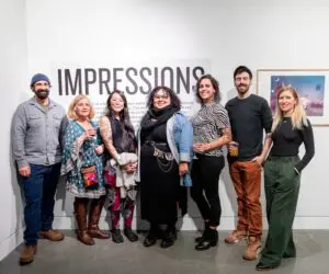 Washington local artists Cody Hagen, Monica Gutierrez-Quarto, Erika Harada, Eileen Jimenez, Thomas Connery pose with curator Lindsey Shepherd in front of Impressions exhibit sign at Field Hall